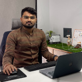 Photo of Sahil H. Narola sitting at desk with laptop and office background
